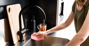 una donna intenta a pulire il lavello di una cucina